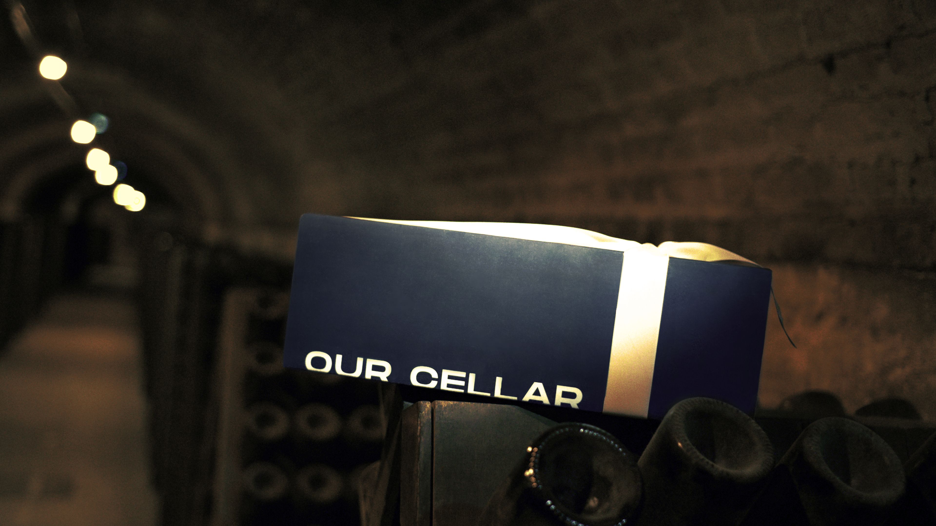The box in a candlelit cellar, on top of bottles in repose. The brand world without the word "luxury."